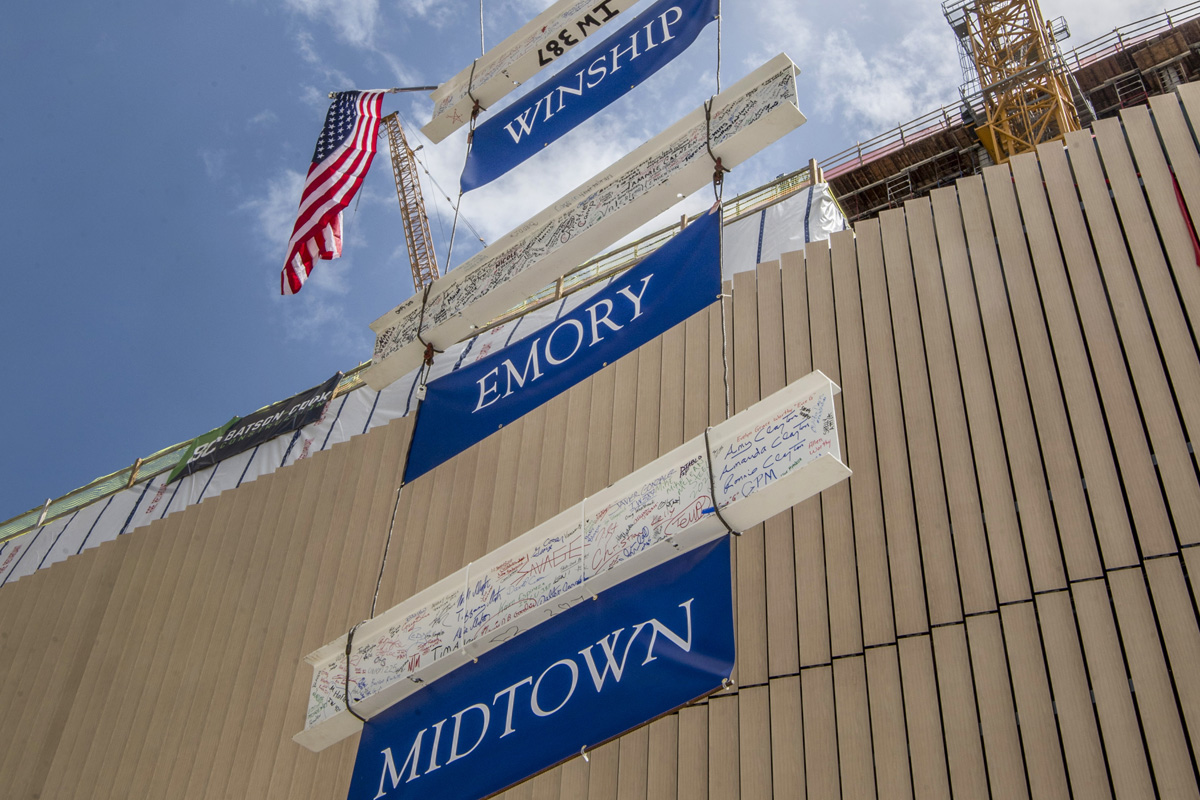 Beam and banners elevating by crane during topping out ceremony.