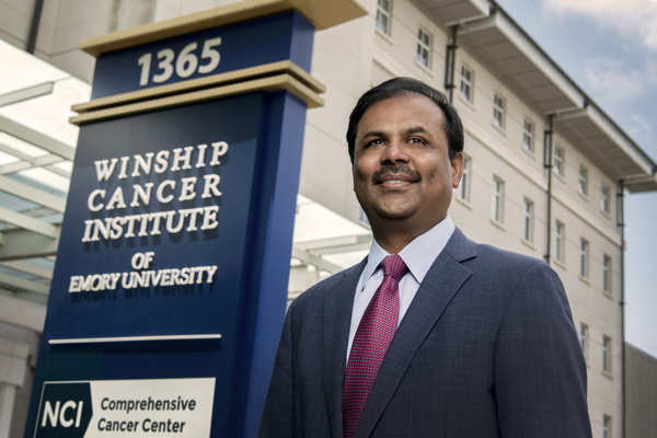 Dr. Ramalingam in front of Winship Cancer Institute sign and building.