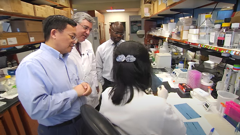 Winship researchers in the lab observe experiment conducted by lab technician