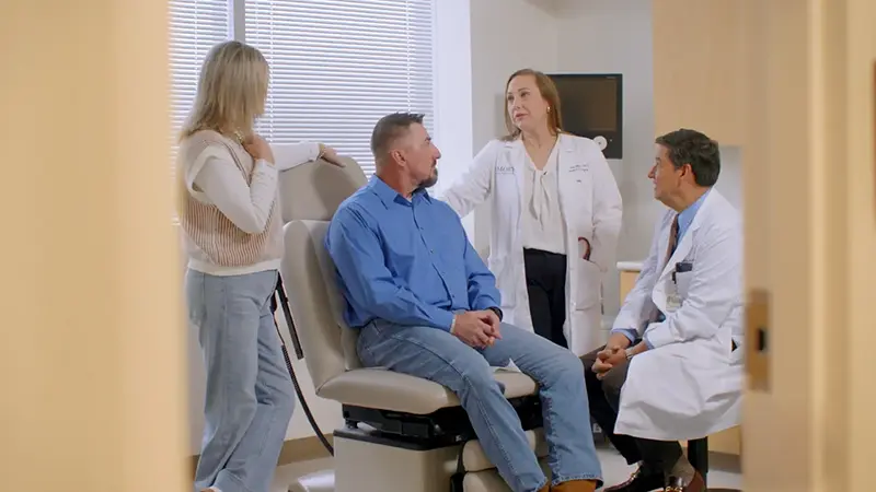 Doctor and physician assistant comforting patient and his spouse.