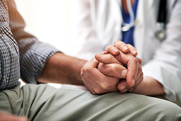 Female doctor consoling a male patient during a checkup (stock image)