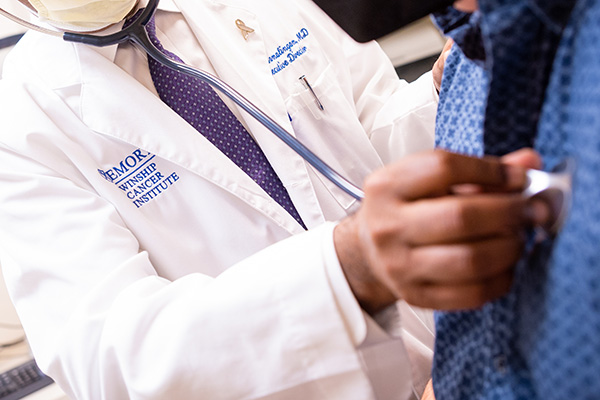 Oncologist holding stethoscope to patient's chest