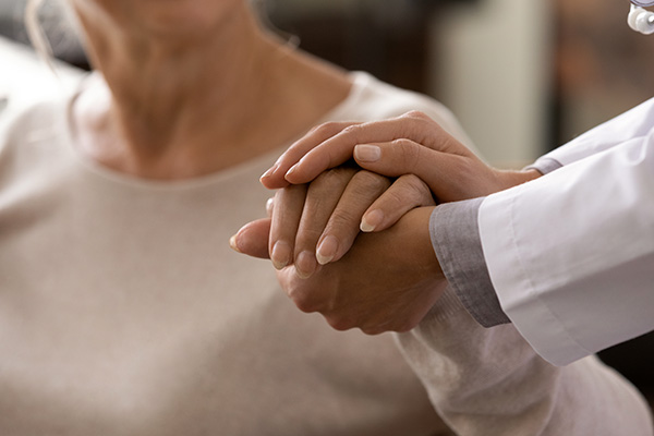 Clinician holding hand and consoling middle aged woman (stock image)