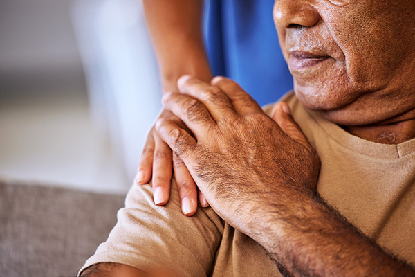 Senior aged man holds health care provider's hand on his shoulder (stock image)