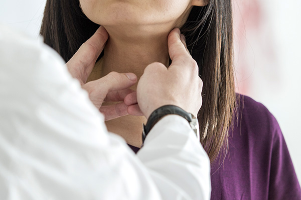 Clinician examining a patient's lymph nodes in throat (stock image)