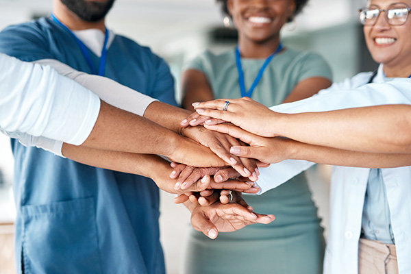 Health care team members place and stack their hands together in the middle of the group (stock image)