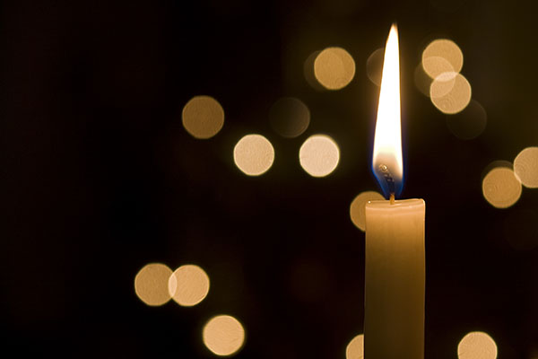 A single lit candle with light reflections in background. (Stock image)