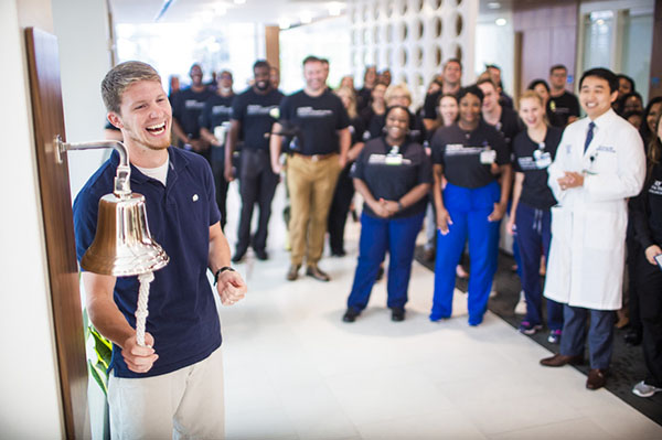 Steven, a patient treat for glioma at Emory Proton Therapy Center, rings the bell in front of care team and staff.