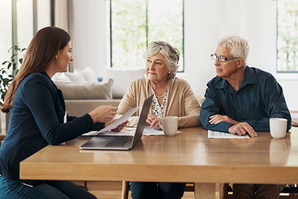 Estate planner speaking to senior couple at a table. (Stock image)