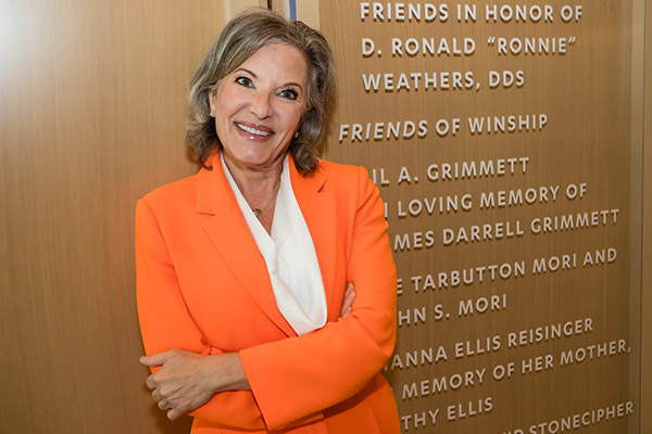 Gail Grimmett leans up against the Winship donor wall with her and her husband's names.