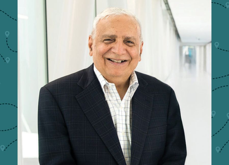 a portrait of an older male with white hair and suit smiling at the camera.