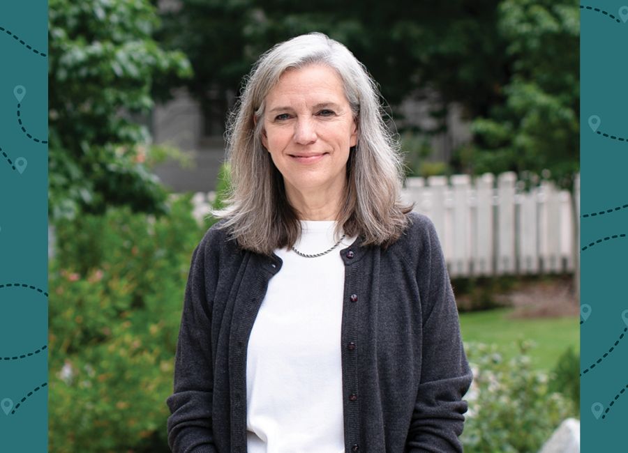 a portrait of a woman with medium long gray hair and smiling to the camera.