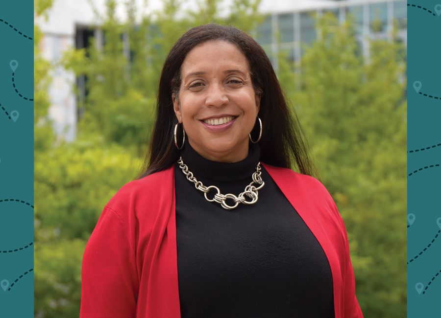 a portrait of a woman with long brown hair wearing a red jacket and smiling to the camera.