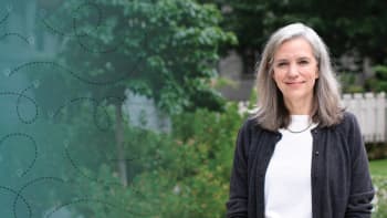 a portrait of a woman with medium long gray hair and smiling to the camera.