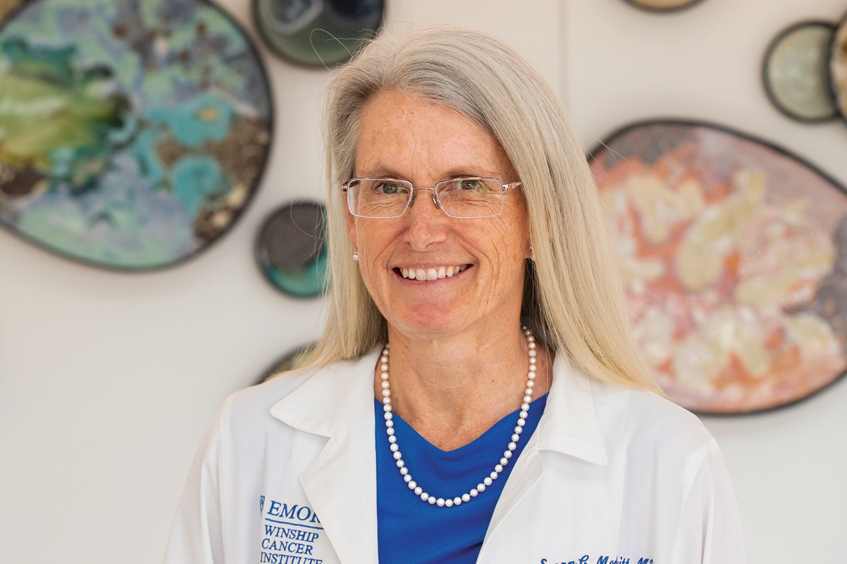 a white female doctor wearing a white coat and glasses and smiling at the camera.