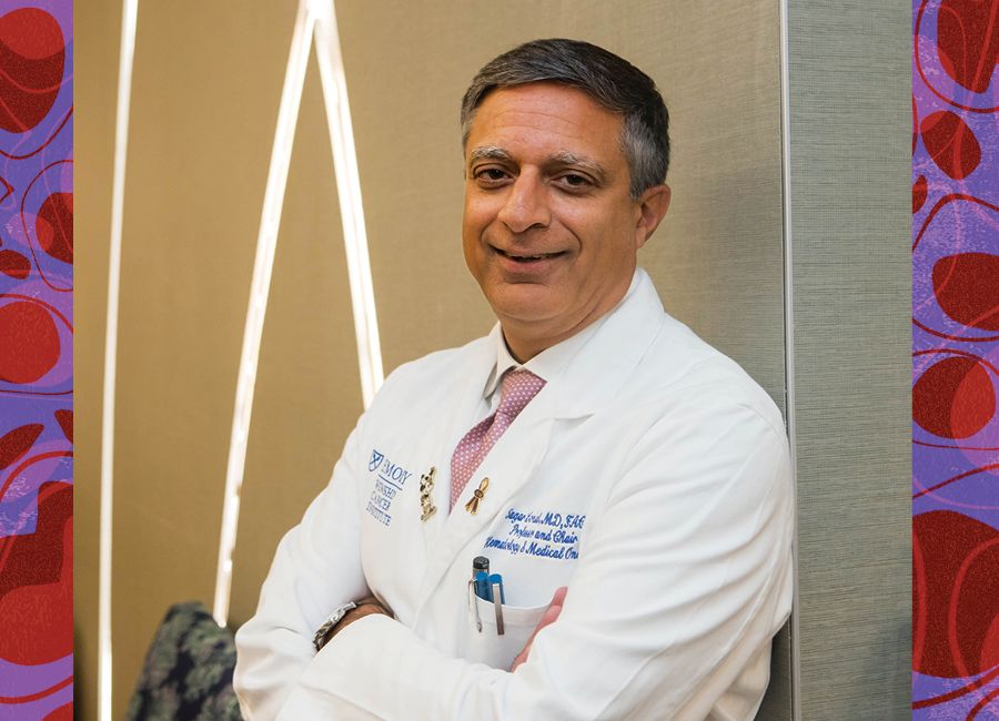 a portrait of a male doctor with his white coat on and smiling to the camera.