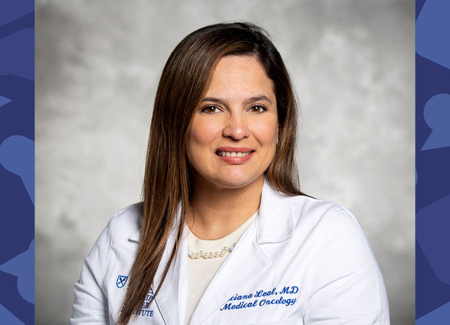 a portrait of a female doctor with dark brown hair to her shoulder, wearing a white coat, and smiling to at the camera.