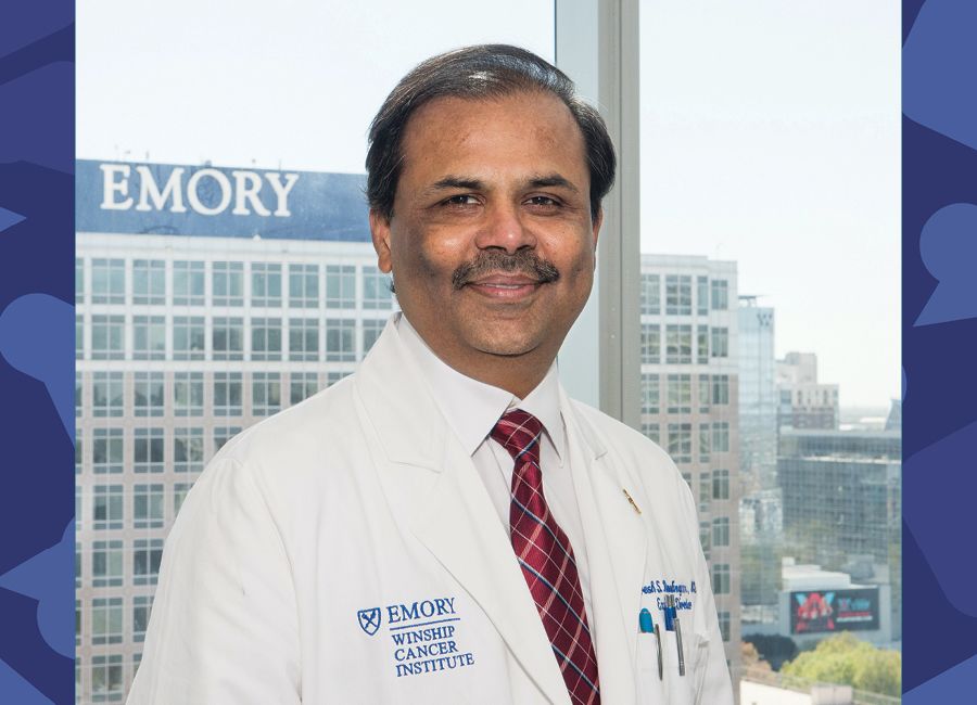 a portrait of a male doctor with his white coat on and smiling to the camera.