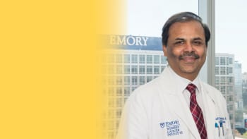 a portrait of a male doctor with his white coat on and smiling to the camera.