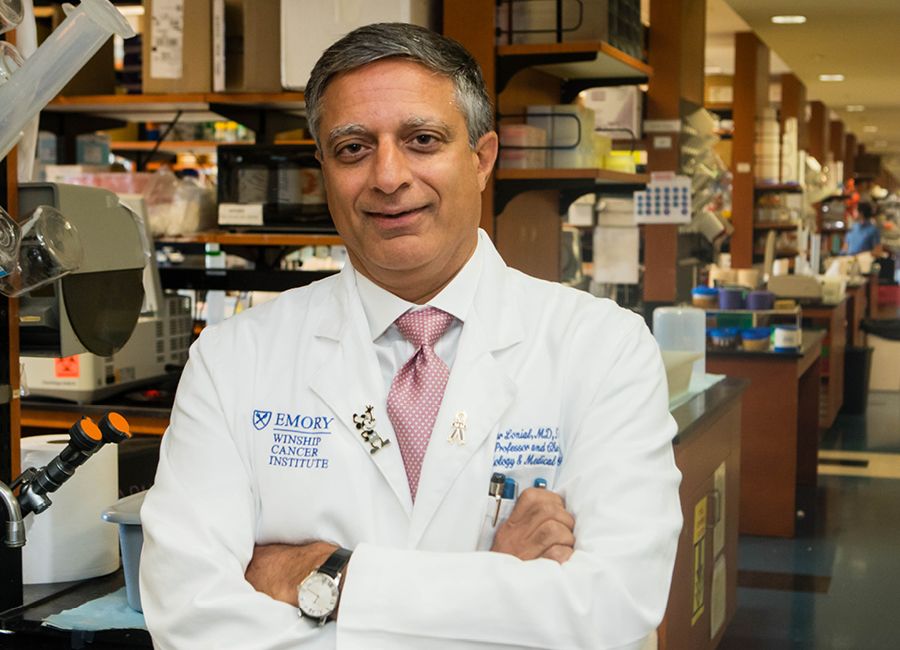 a portrait of a male doctor with his white coat on and smiling to the camera.