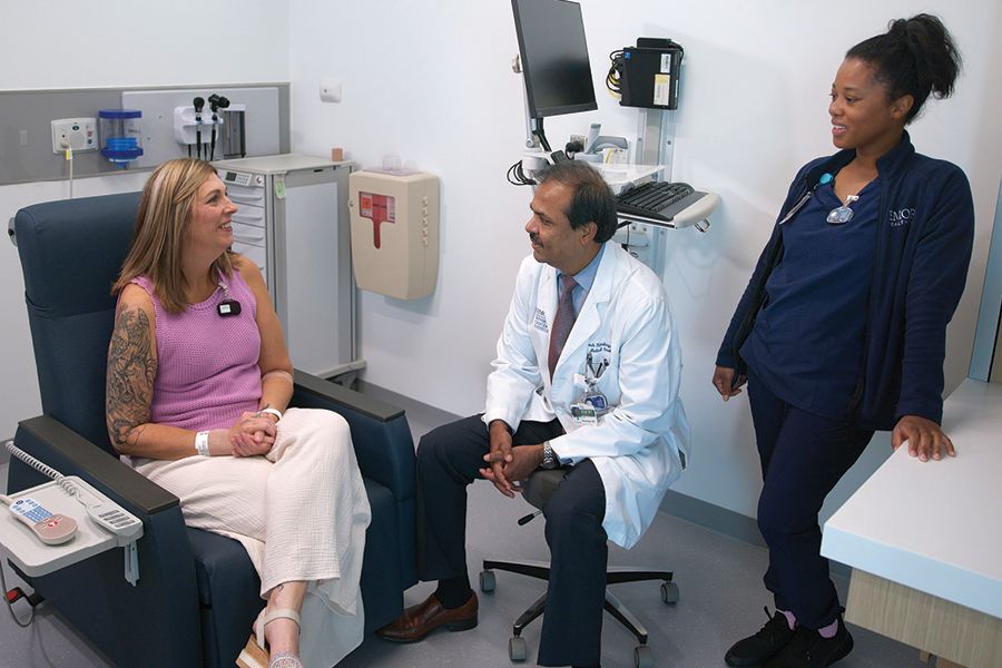 a photography of a female patient talking to her medical team comprised of a doctor and a nurse.