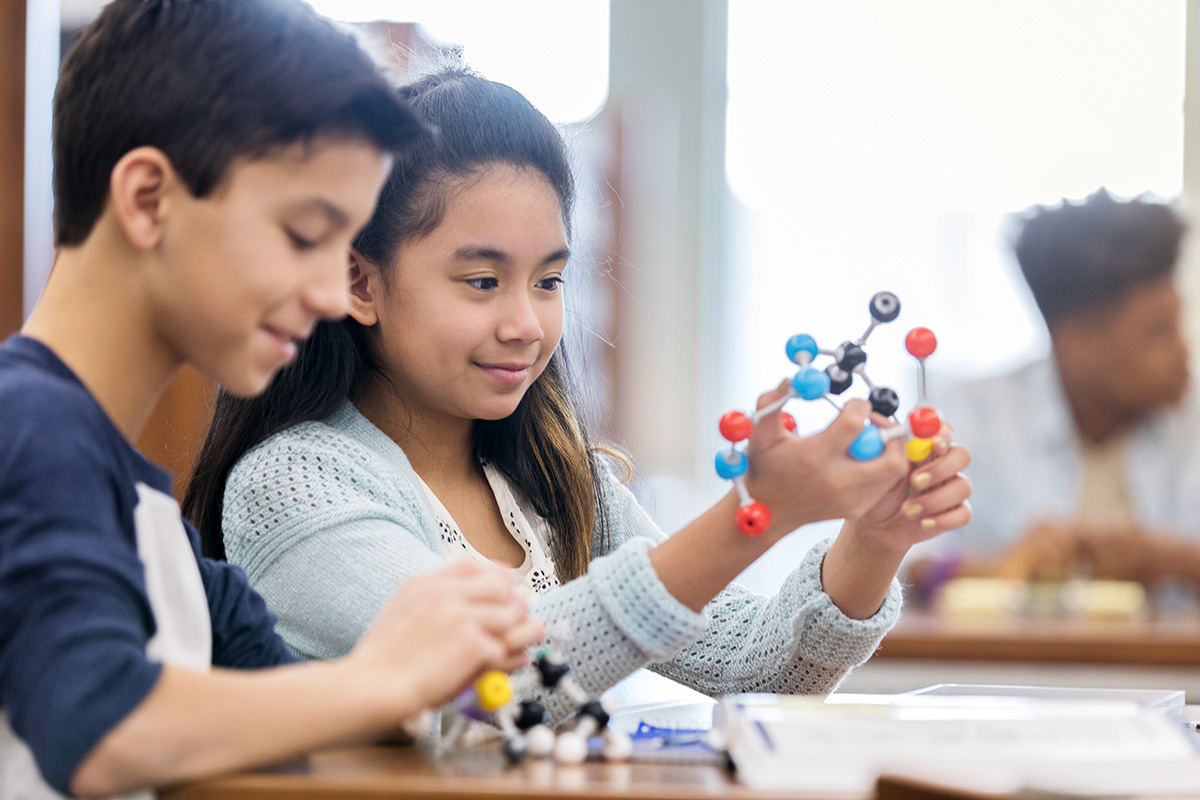 Two young students interacting with STEM tools