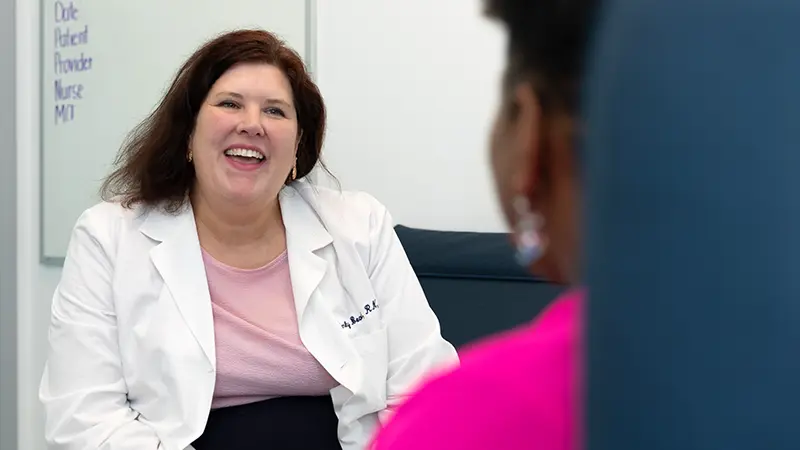 Clinician smiling while talking to a patient in exam room.