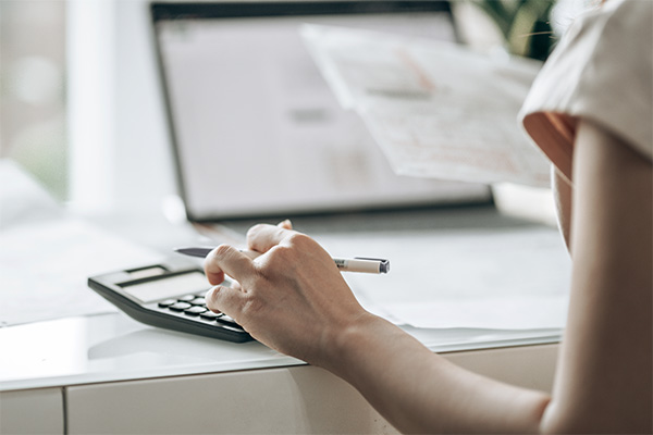 Woman using calculator and checking her bills on a computer (stock image)