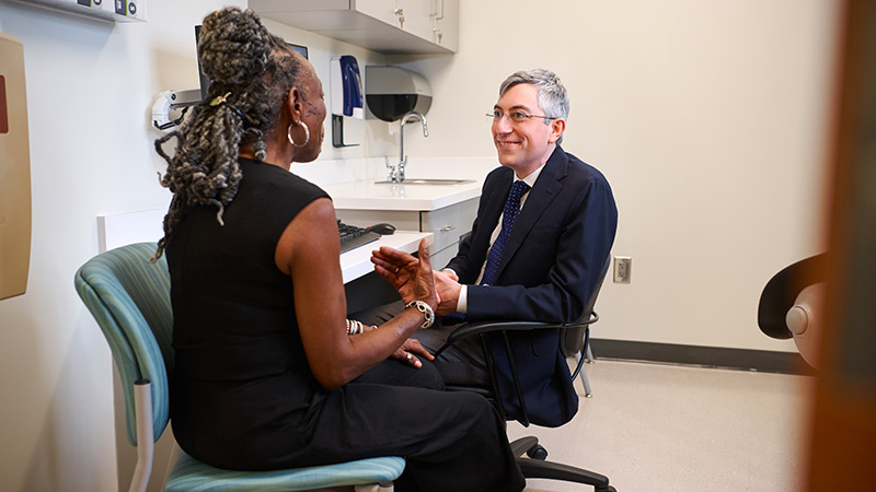 Dr. Daniel Halperin sitting and listening to a patient in an exam room.