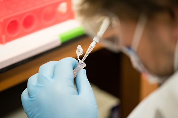 Lab technician using pipette to fill a vial