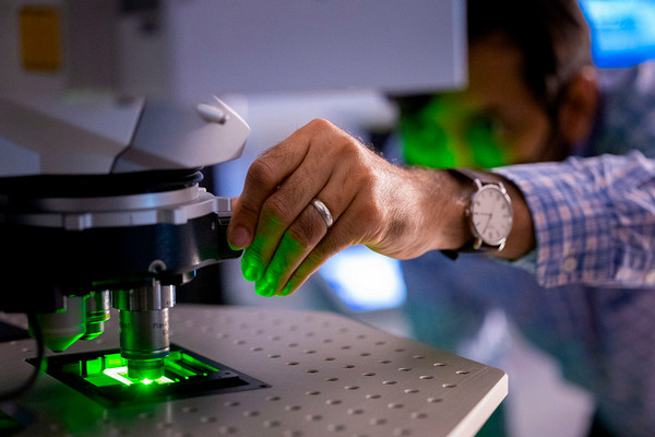 Imaging lab technician preparing high-powered microscope