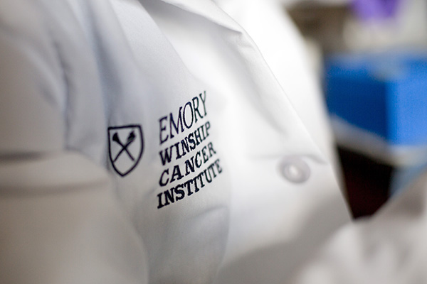 Embroidered Winship logo on the lapel of a white lab coat