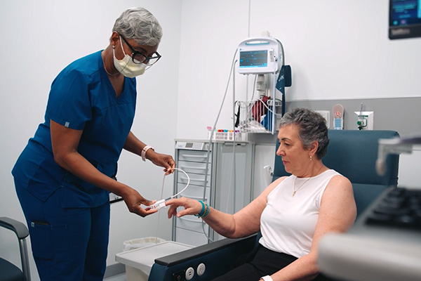 Medical assistant checks Marsha's heart rate with monitor device