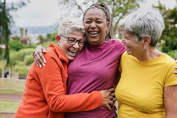 Three middle-aged women embracing and laughing (stock image)