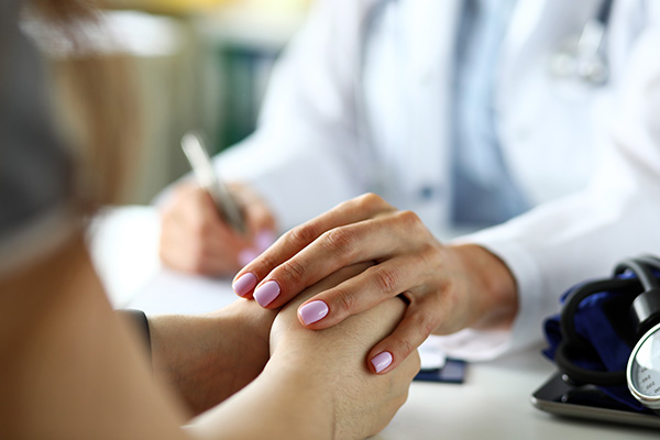 Female physician comforting patient by holding their hand (stock image)