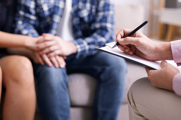 Psychiatrist taking notes during session with a couple (stock image)