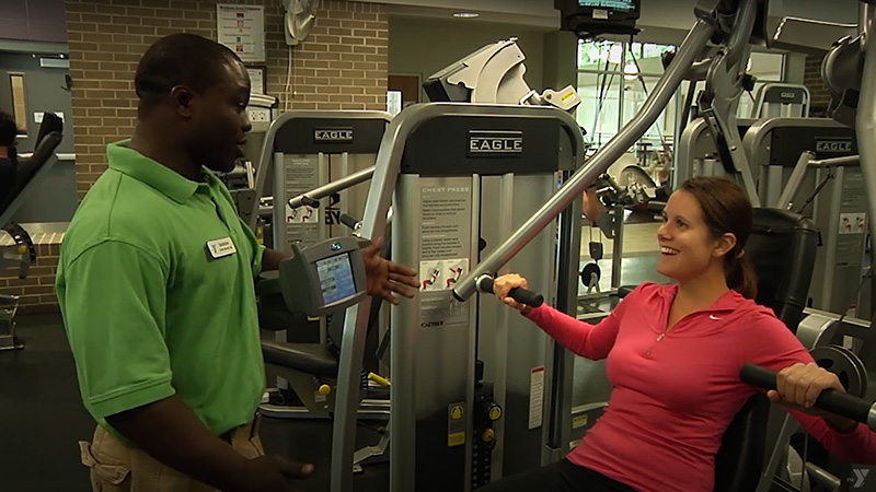 Fitness trainer talking to a woman on a weight machine