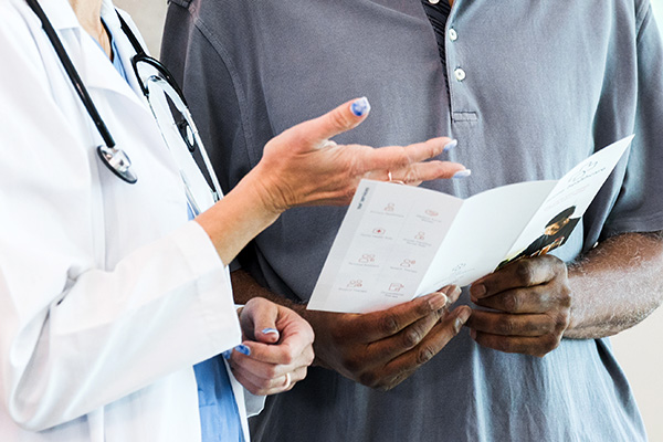 Clinician discussing informational brpochure with a male patient (stock image)