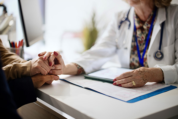 Clinician holding hands with her patients during a consultation. (stock image)